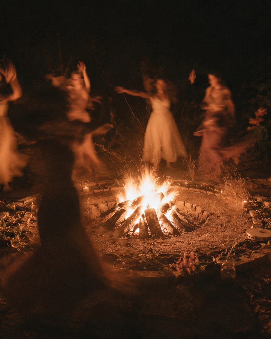 Women dancing together around a fire at night.