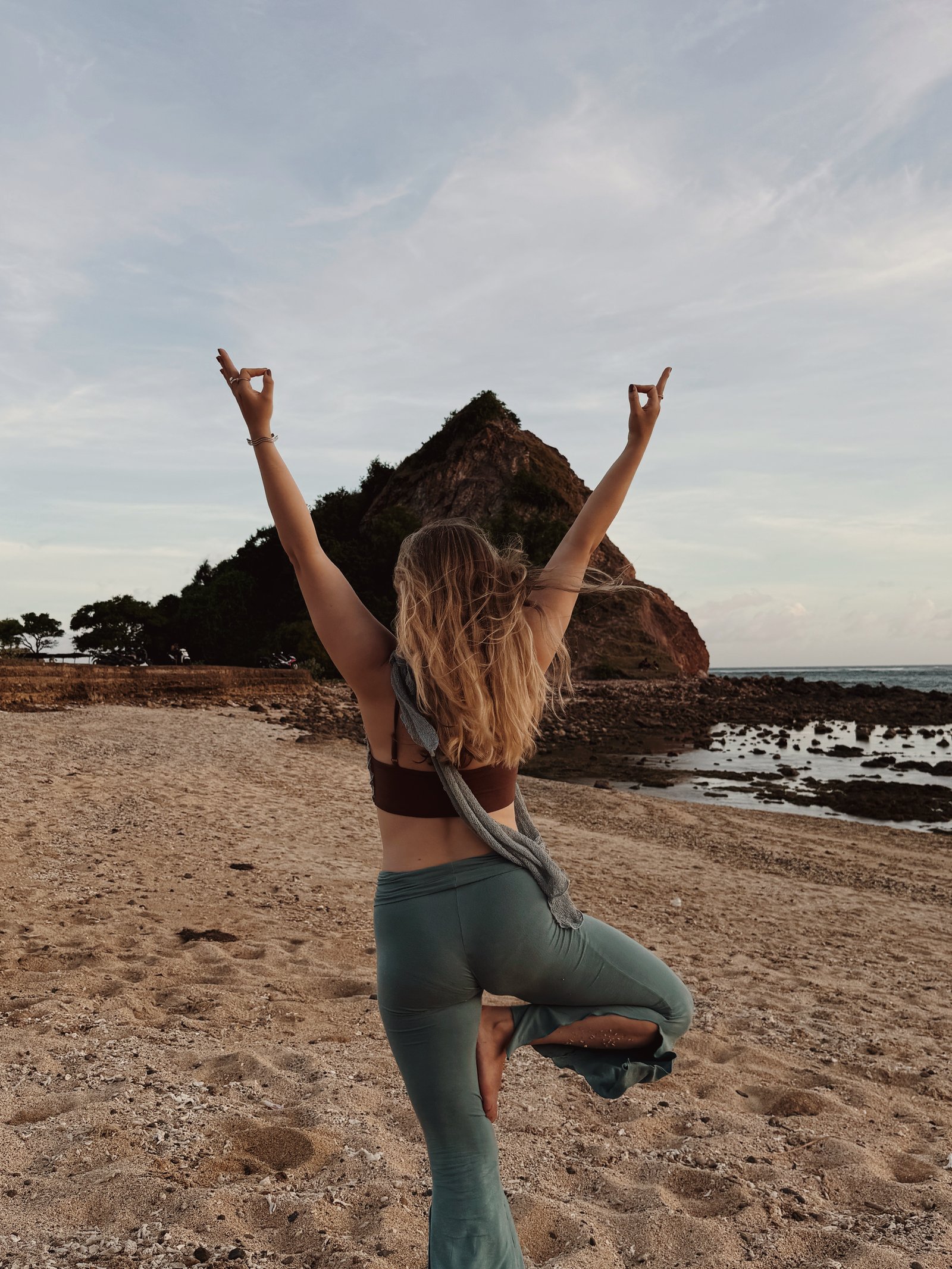 Anna in a standing yoga pose, arms raised, outdoors.