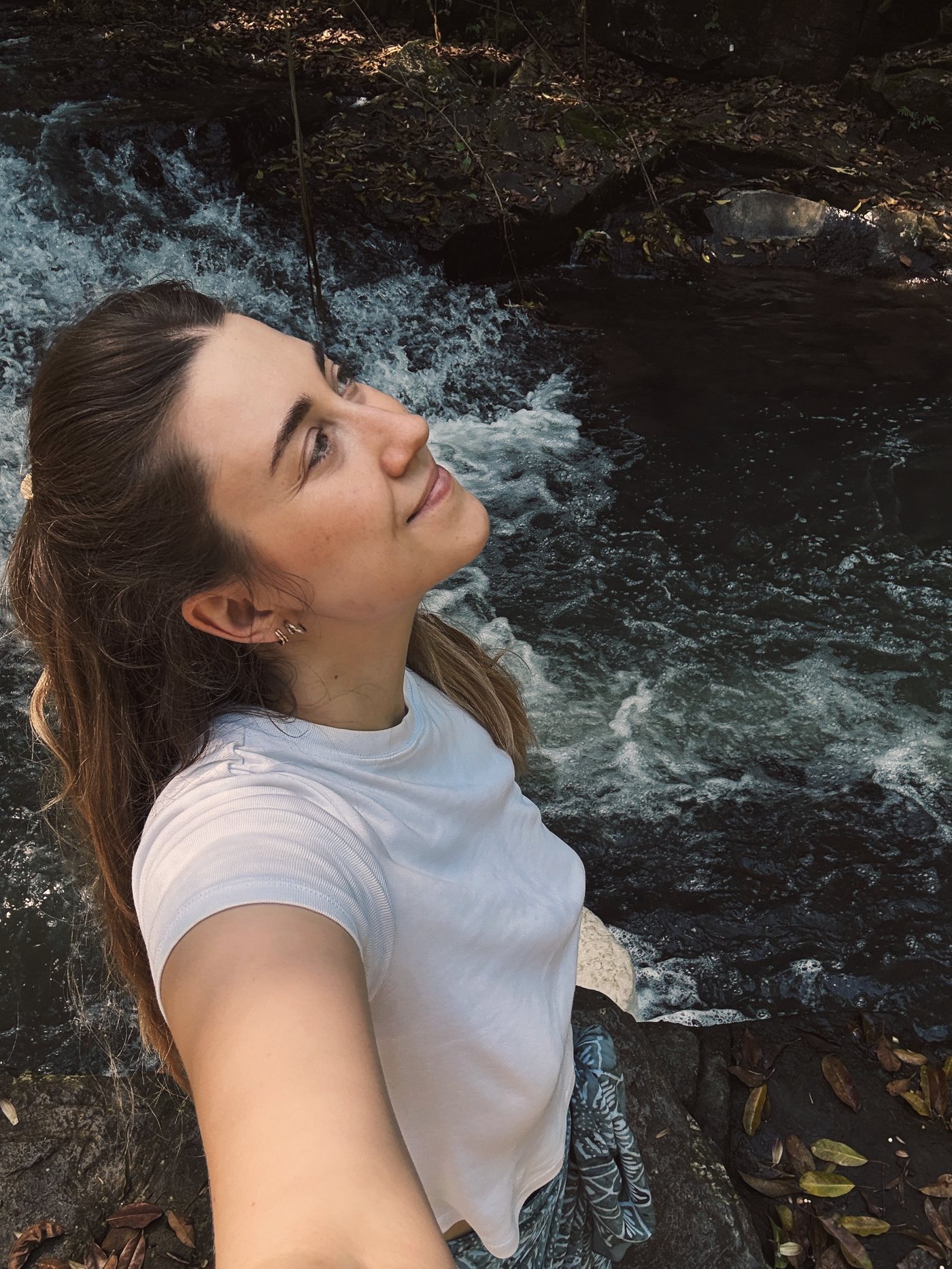 Anna, profile portrait, looking up, by a waterfall.